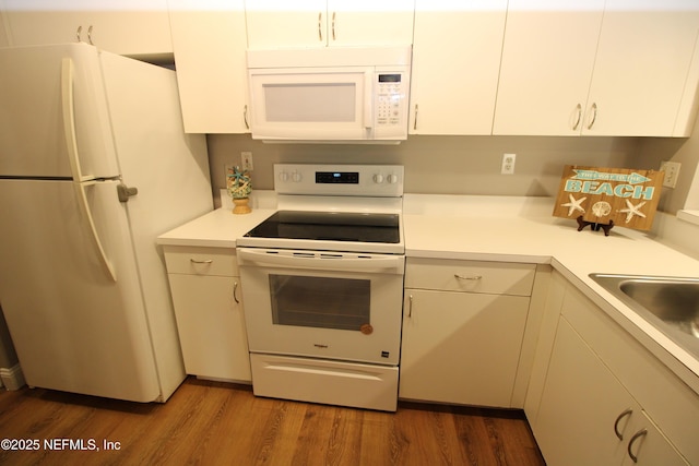 kitchen featuring white appliances, white cabinets, and wood finished floors