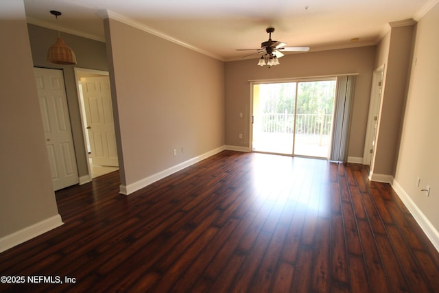 spare room featuring crown molding, baseboards, and dark wood-style flooring