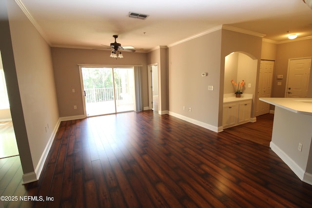 unfurnished living room featuring ornamental molding, dark wood-type flooring, visible vents, and baseboards