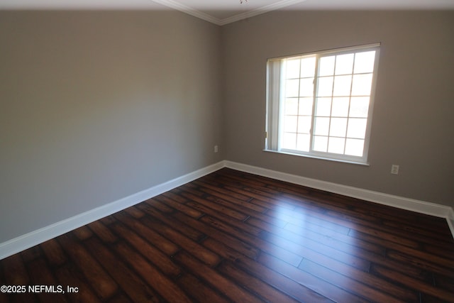 spare room featuring dark wood-style floors, crown molding, and baseboards