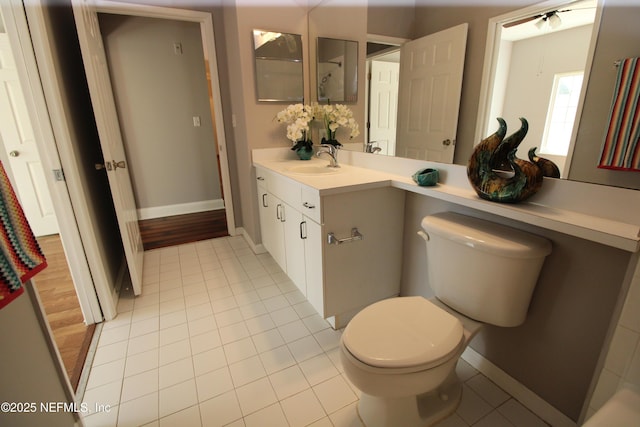 bathroom with tile patterned flooring, baseboards, vanity, and toilet