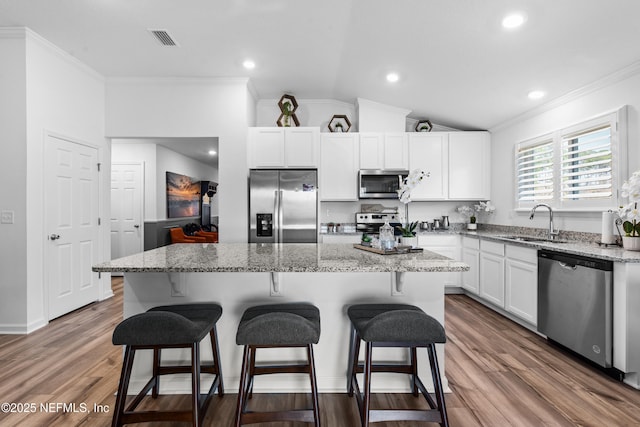 kitchen featuring visible vents, a sink, wood finished floors, white cabinetry, and stainless steel appliances