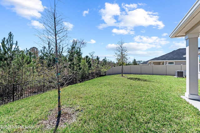 view of yard with central AC and fence