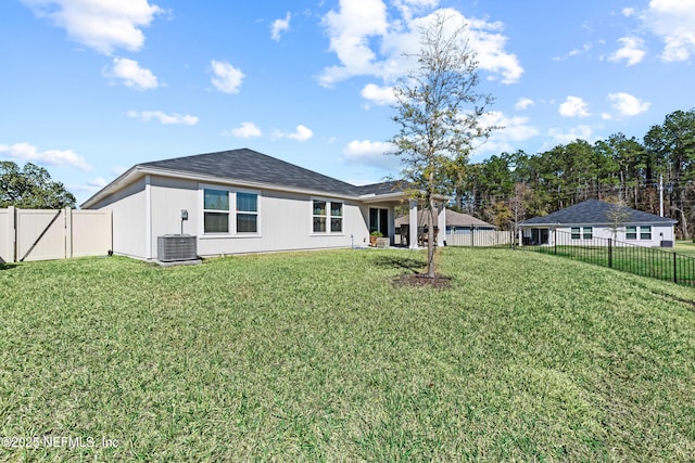 back of property with a lawn, cooling unit, and a fenced backyard