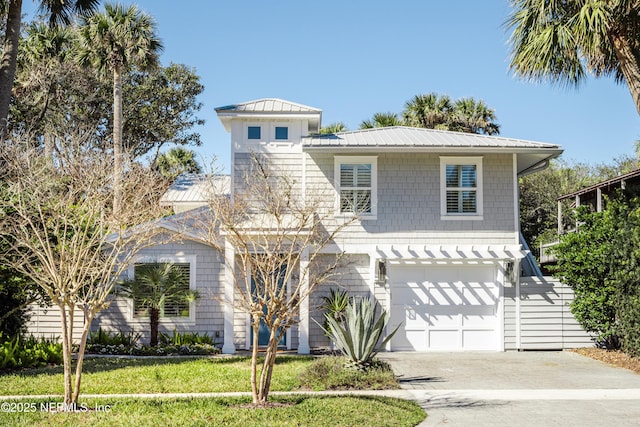 view of front of property featuring an attached garage, driveway, metal roof, and a front yard