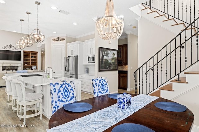 dining space featuring stairway, a notable chandelier, light wood-style floors, and visible vents