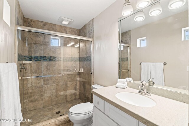 full bath with vanity, toilet, and a shower stall