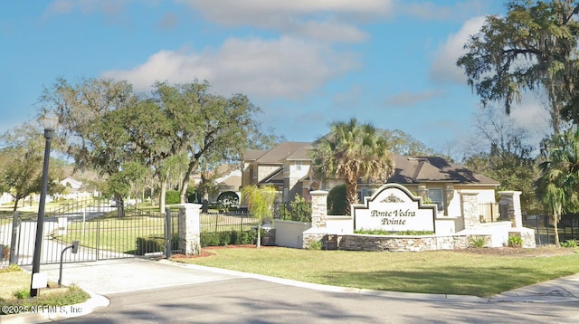 community / neighborhood sign with a gate, a residential view, a yard, and fence