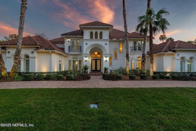mediterranean / spanish home with stucco siding, french doors, and a balcony