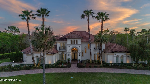 mediterranean / spanish house with french doors, stucco siding, a front yard, and a tile roof