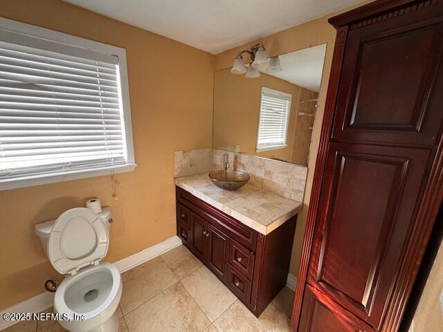 bathroom featuring toilet, a shower with shower curtain, vanity, baseboards, and tile patterned floors