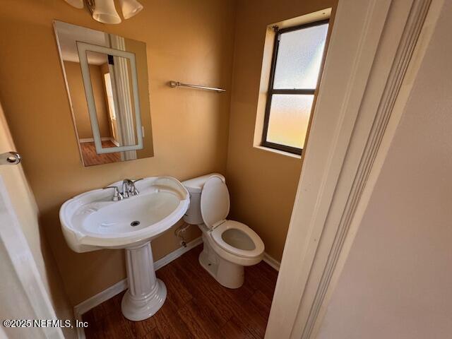 half bathroom featuring baseboards, a sink, toilet, and wood finished floors