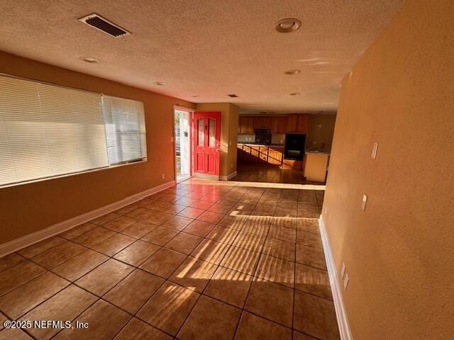 interior space with visible vents, a textured wall, a textured ceiling, and baseboards