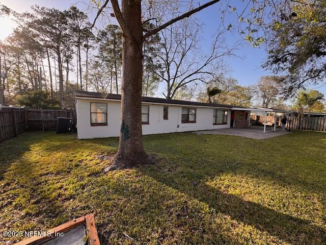 rear view of house featuring a yard, a patio area, and a fenced backyard