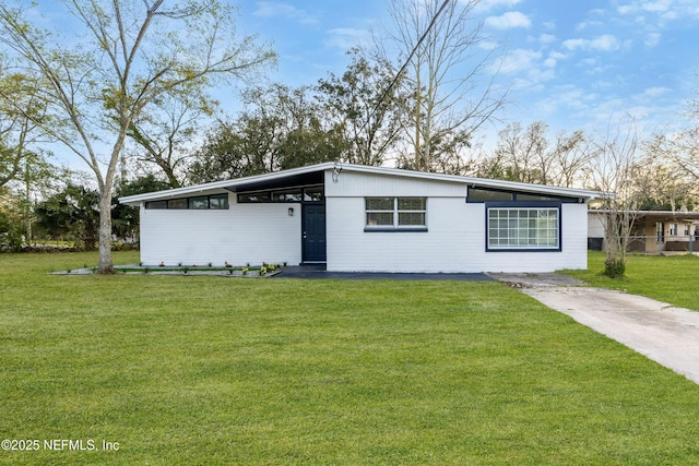 mid-century modern home featuring an attached carport, a front lawn, and concrete driveway