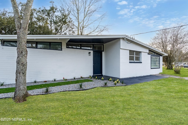 mid-century home featuring a front yard and an attached carport