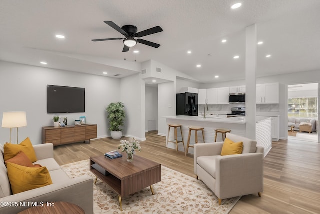 living area with lofted ceiling, visible vents, light wood-style flooring, and recessed lighting