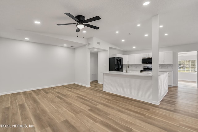 kitchen with light wood-style flooring, vaulted ceiling, stainless steel appliances, light countertops, and white cabinetry