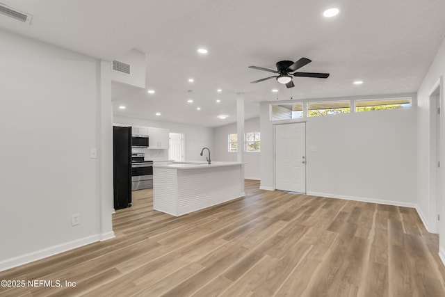 kitchen with light wood-style flooring, appliances with stainless steel finishes, visible vents, and light countertops