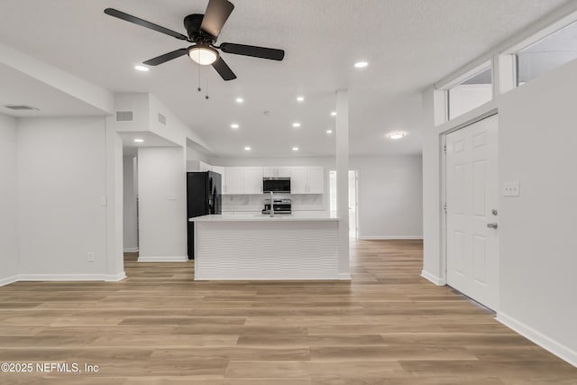 kitchen featuring light wood-style flooring, visible vents, light countertops, range, and stainless steel microwave