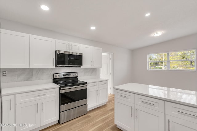 kitchen with recessed lighting, light countertops, appliances with stainless steel finishes, white cabinets, and light wood-type flooring