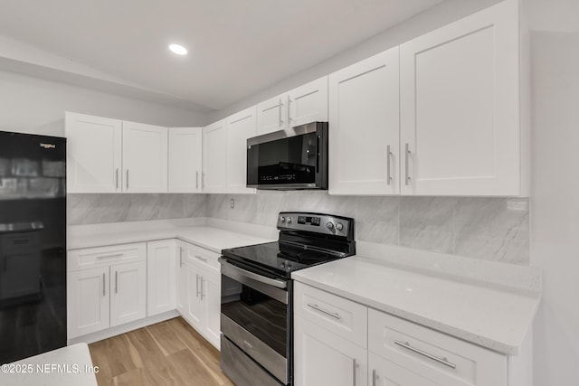 kitchen with stainless steel appliances, tasteful backsplash, light countertops, light wood-style flooring, and white cabinets