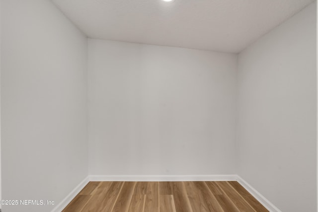 spare room featuring baseboards and wood finished floors