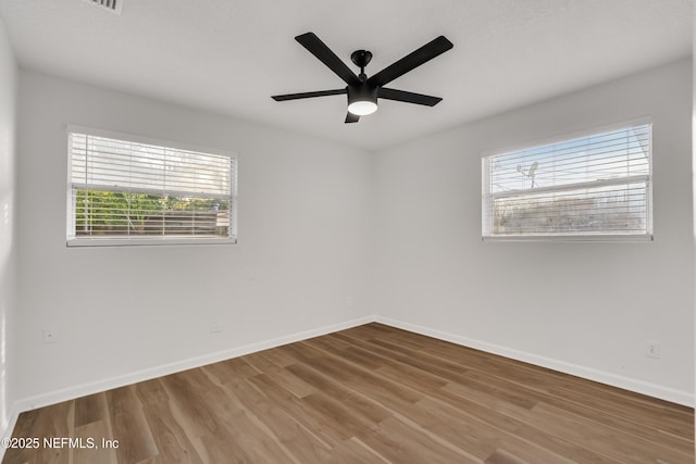 unfurnished room featuring wood finished floors, a ceiling fan, and baseboards