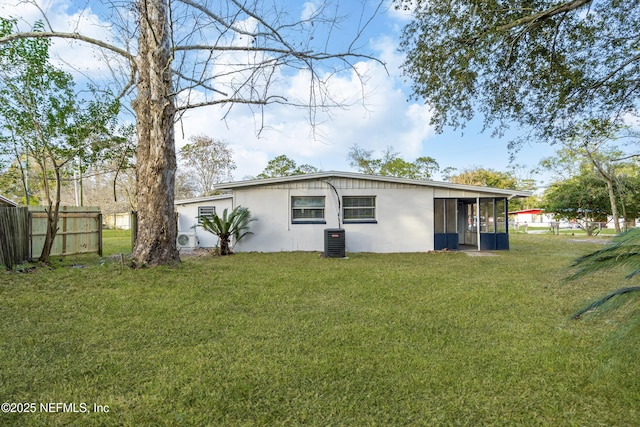 rear view of property with central AC unit, a sunroom, fence, and a lawn