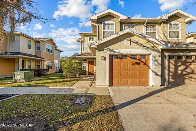 townhome / multi-family property with stucco siding, a garage, and driveway