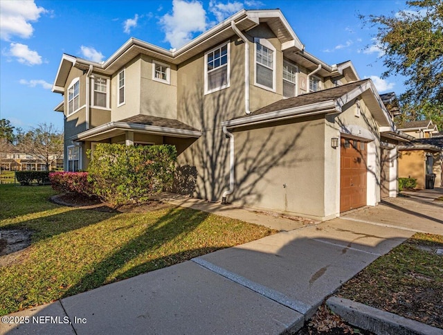 view of front of house featuring stucco siding, an attached garage, and a front yard