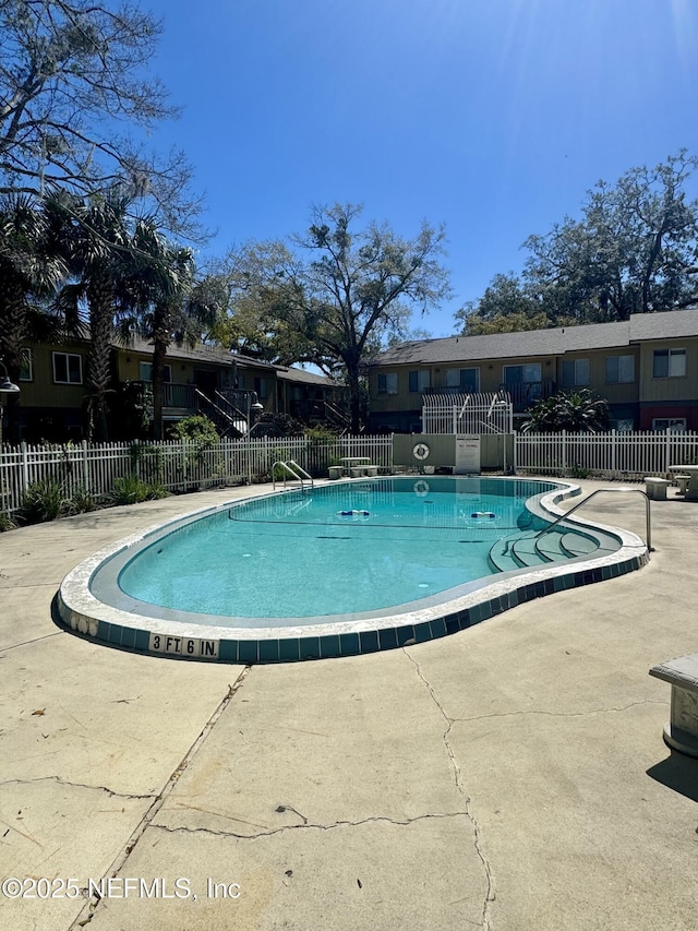 community pool with a patio area and fence