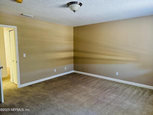 carpeted spare room with a textured ceiling, visible vents, and baseboards