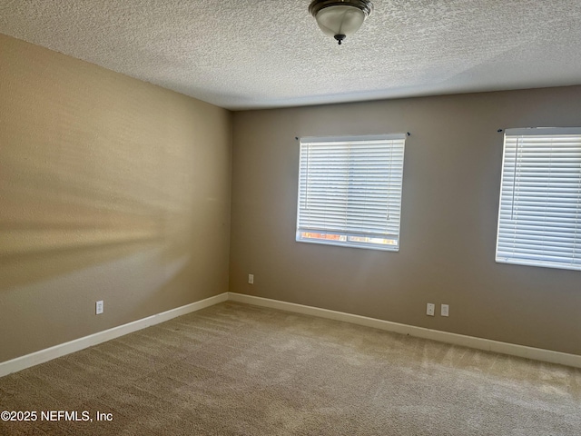 unfurnished room with carpet floors, baseboards, and a textured ceiling