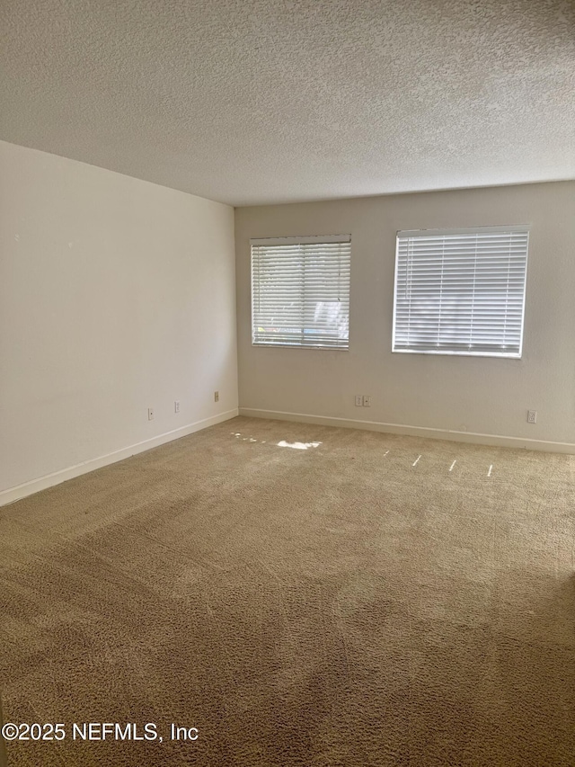 carpeted empty room with a textured ceiling and baseboards