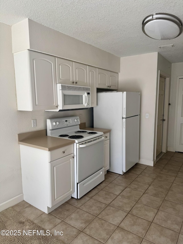 kitchen with a textured ceiling, light tile patterned floors, white appliances, white cabinetry, and light countertops