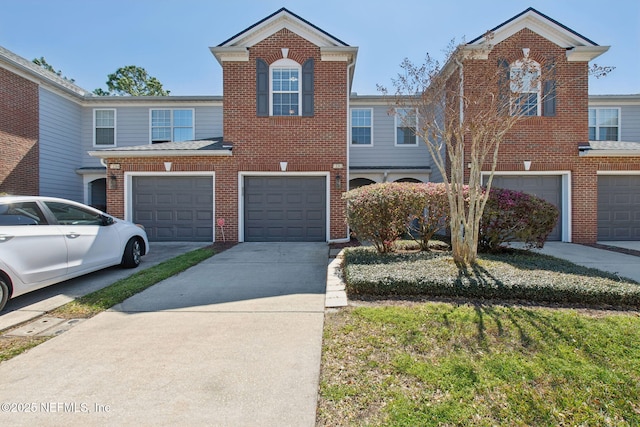 townhome / multi-family property featuring brick siding, driveway, and an attached garage