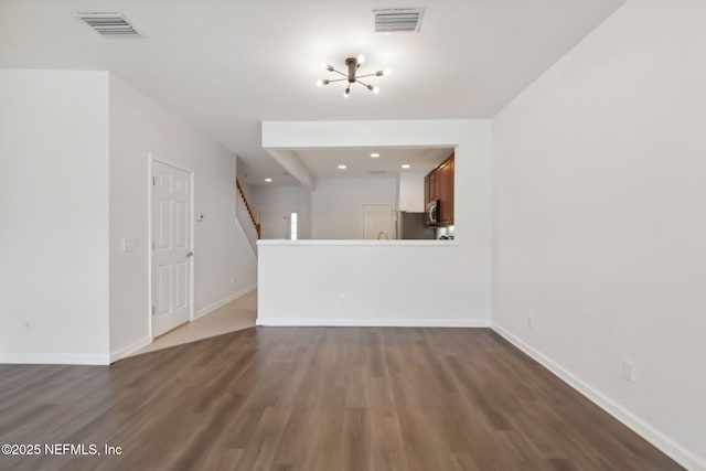 unfurnished living room with dark wood-style flooring, visible vents, stairway, and baseboards