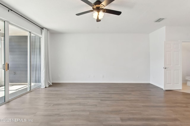 empty room with a ceiling fan, visible vents, baseboards, and wood finished floors