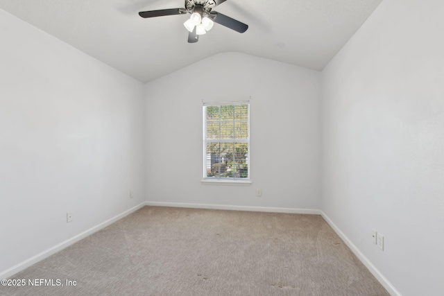 carpeted empty room with vaulted ceiling, a ceiling fan, and baseboards