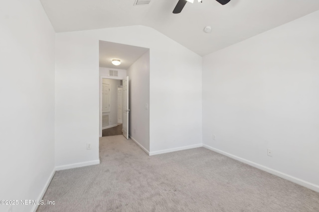 empty room featuring carpet flooring, a ceiling fan, visible vents, vaulted ceiling, and baseboards