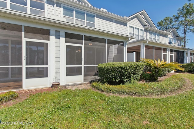 back of house with a lawn and a sunroom