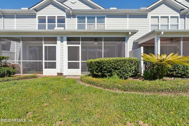 rear view of property featuring a yard, a sunroom, and ceiling fan