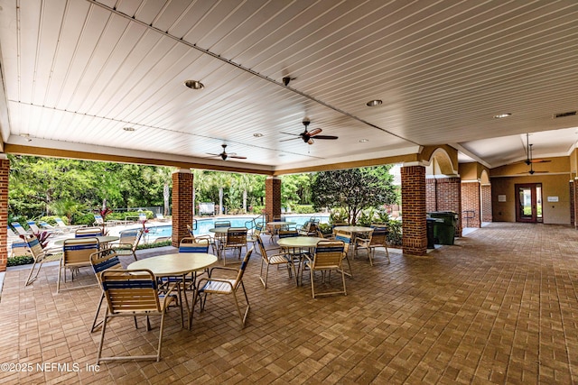 view of patio featuring outdoor dining space, ceiling fan, and a community pool