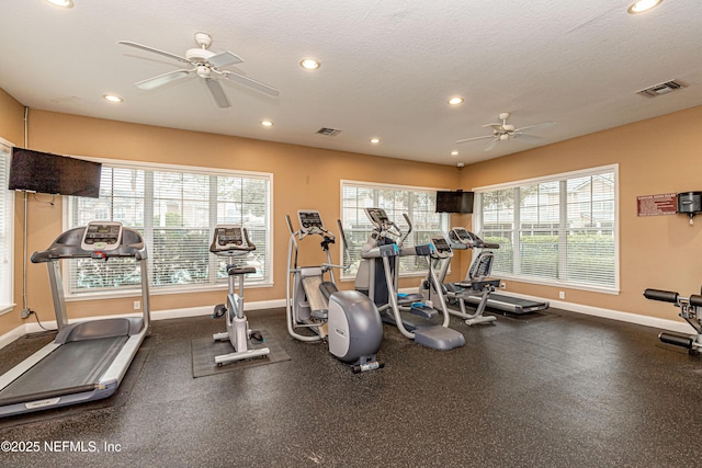 exercise room with a textured ceiling, baseboards, visible vents, and a healthy amount of sunlight