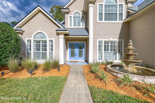 property entrance featuring french doors, roof with shingles, and stucco siding