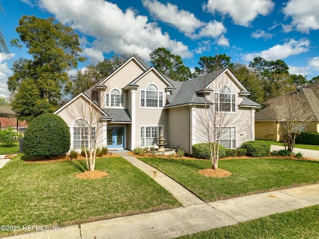 traditional-style home featuring stucco siding, french doors, a front yard, and a shingled roof