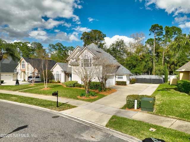 view of front of home with a garage, concrete driveway, a front lawn, and fence