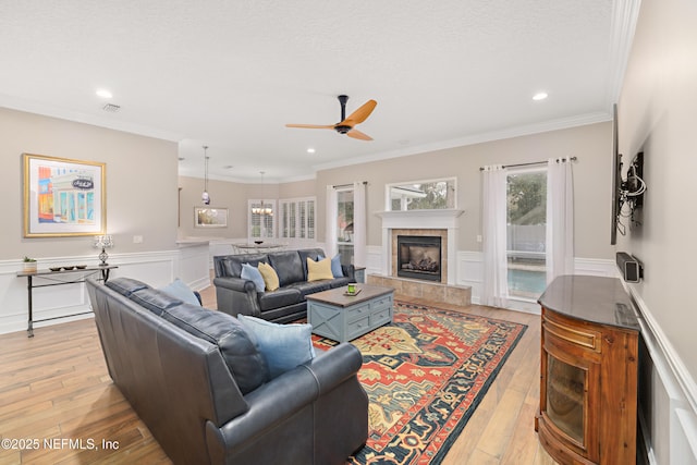 living room with wainscoting, light wood-style flooring, and ornamental molding