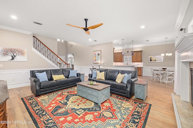 living area with visible vents, light wood-style flooring, crown molding, and stairway